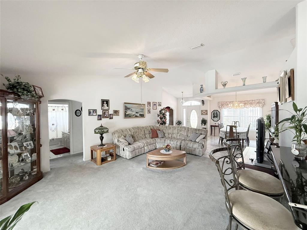 A living room with a sectional sofa, carpeted floors, and an adjacent dining area — 22 COLORADO DRIVE, PALM COAST, FL