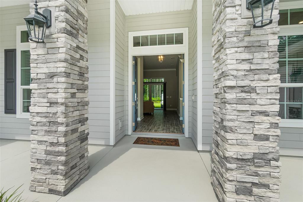 A front entryway with stone-clad columns, a light-colored exterior, and a view into the home — 2505 CABBAGE HAMMOCK ROAD, ST AUGUSTINE, FL