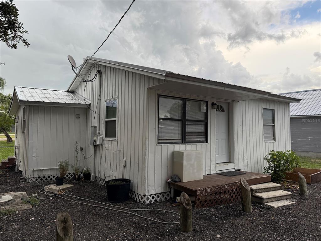 A white, single-story house with vertical siding and a metal roof features a small porch — 101 S ROGERS AVENUE, ARCADIA, FL