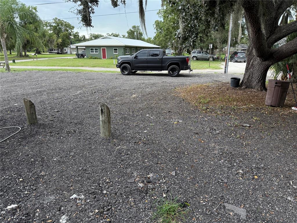 A gravel driveway leads to a green house with a black pickup truck parked outside — 101 S ROGERS AVENUE, ARCADIA, FL