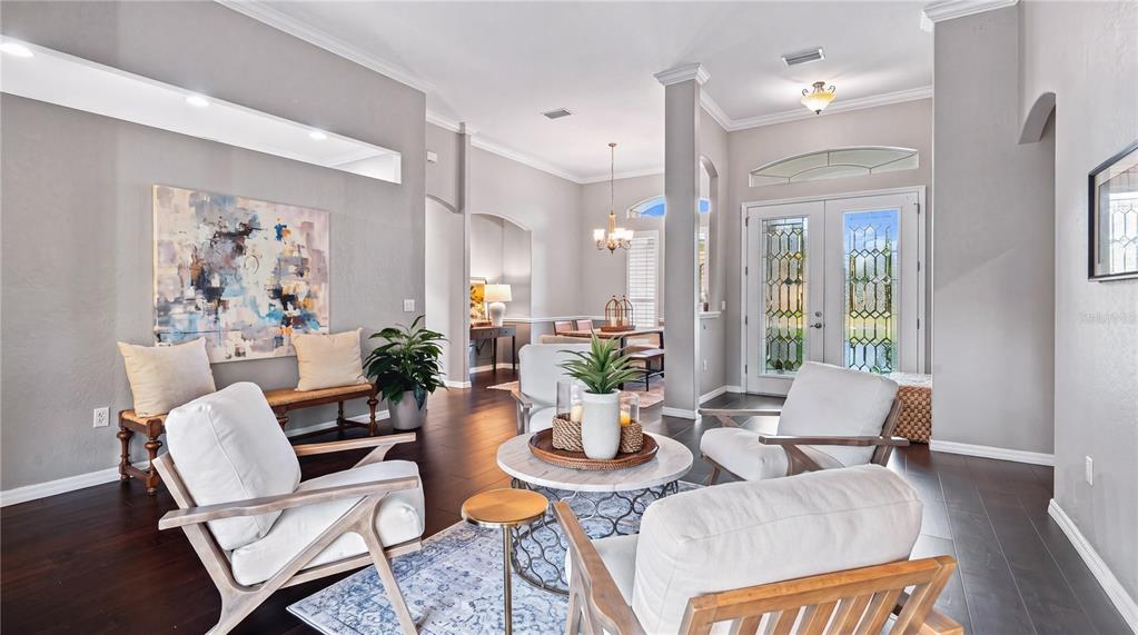 A living room with white armchairs, a round coffee table, and dark hardwood floors — 16203 33RD COURT E, PARRISH, FL