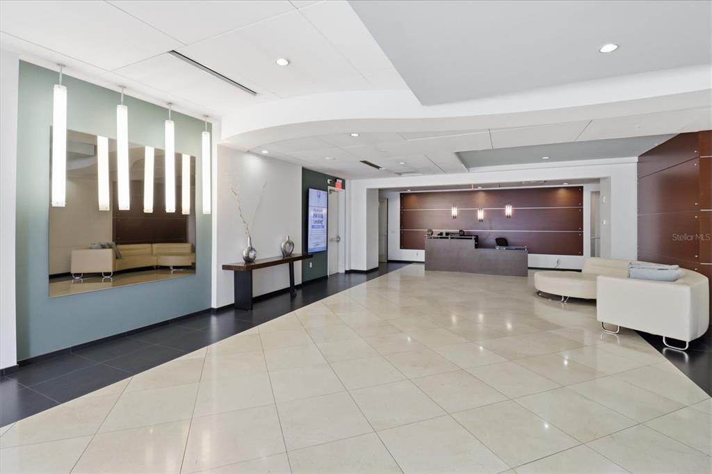 A modern office lobby features a reception desk, tiled floors, and a large wall mirror — 101 S EOLA DRIVE UNIT 1104, ORLANDO, FL