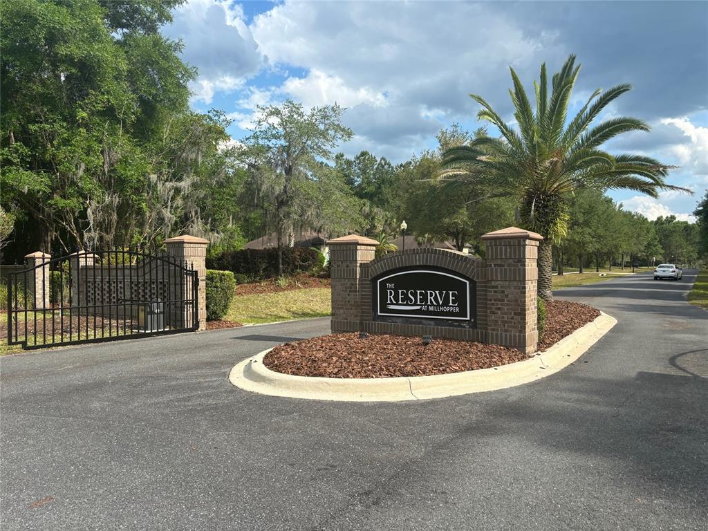 The entrance to a gated residential community features a brick sign and a palm tree — 8845 NW 58TH LANE, GAINESVILLE, FL