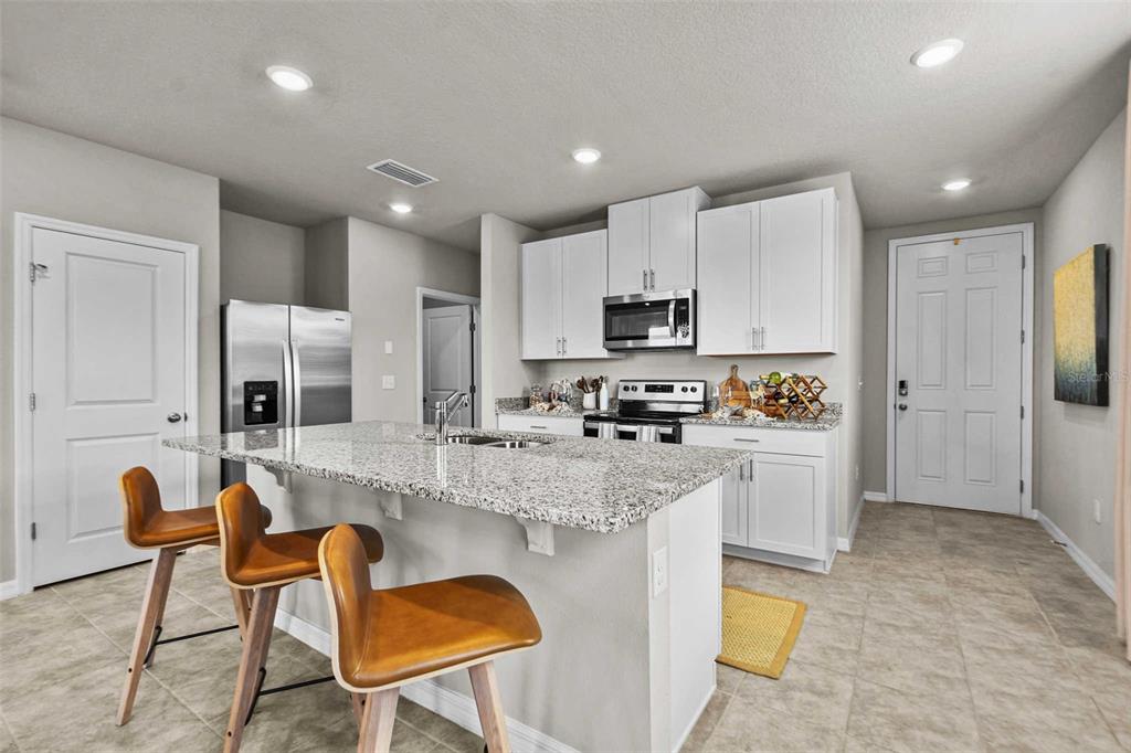 A kitchen with white cabinets, granite countertops, a center island with bar stools, and stainless appliances — 8683 HOLLY GROVE COURT UNIT Calistoga, RIVERVIEW, FL