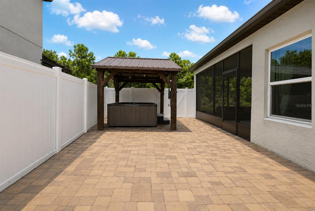 A backyard patio features a hot tub under a wooden gazebo and a screened-in porch — 3485 MIDDLEBROOK PLACE, HARMONY, FL