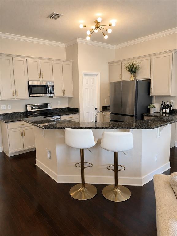 A kitchen with light gray cabinets and dark countertops overlooks a living room with sofa — 1018 GREEN GATE BOULEVARD, GROVELAND, FL