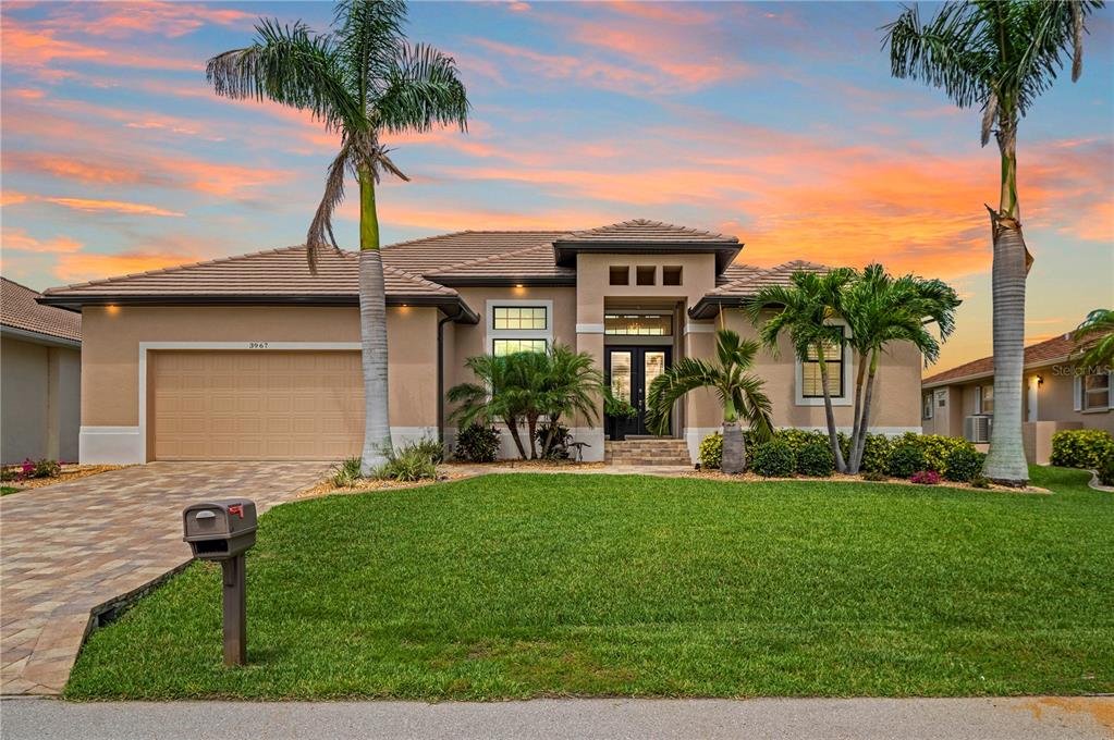 A single-story house with a tan stucco exterior, a paved driveway, and two tall palm trees — 3967 SAN PIETRO COURT, PUNTA GORDA, FL