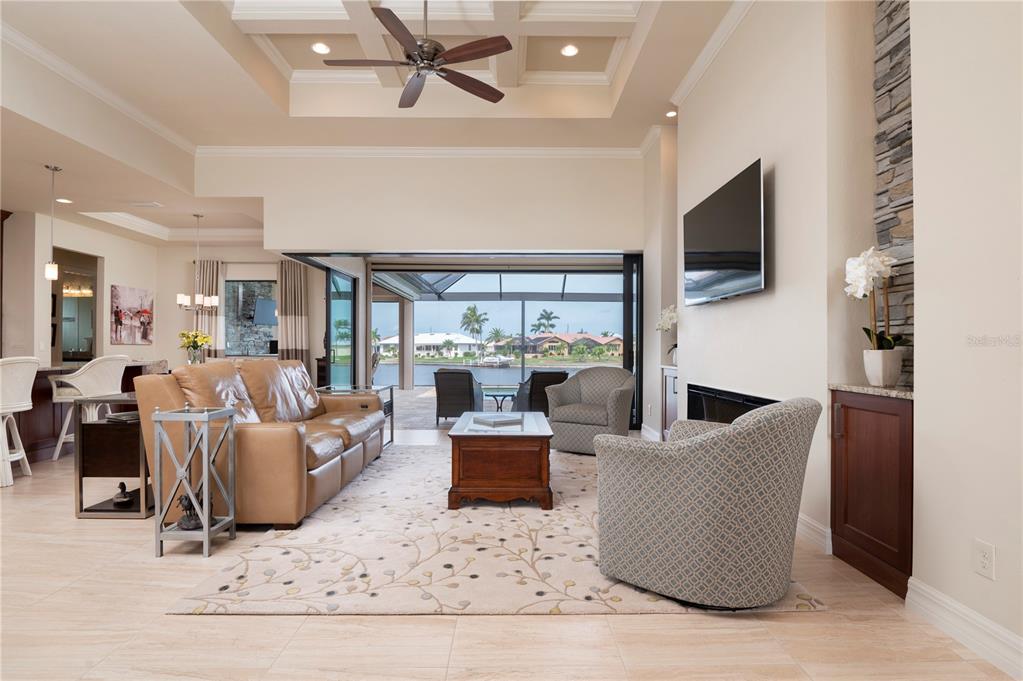 A living room with a coffered ceiling, leather sofa, and sliding doors opening to a pool — 3967 SAN PIETRO COURT, PUNTA GORDA, FL