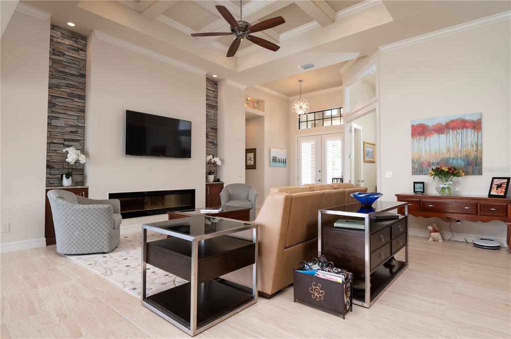 A living room features a stone fireplace, a flat-screen television, and a coffered ceiling — 3967 SAN PIETRO COURT, PUNTA GORDA, FL