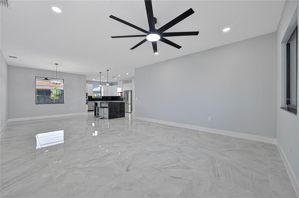 An open-concept living area features large gray marble-look floor tiles and a modern ceiling fan — 1313 NE 7TH AVENUE, CAPE CORAL, FL