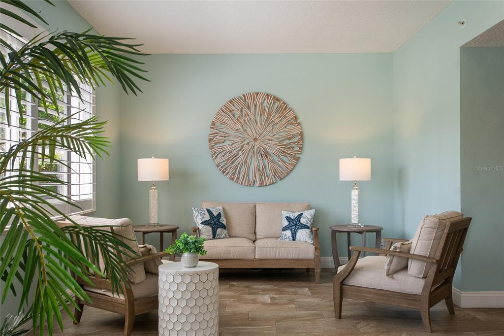 A coastal-themed sitting area features a beige loveseat, two armchairs, and a round wall sculpture — 8700 RIDGEWOOD AVENUE UNIT 205B, CAPE CANAVERAL, FL