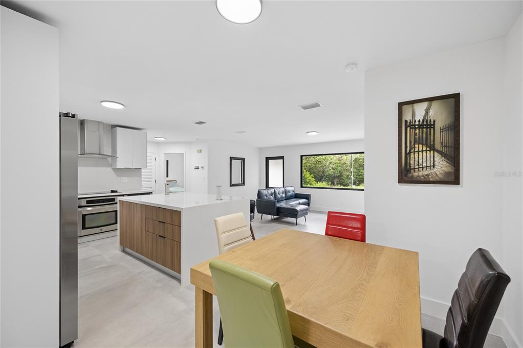 An open-concept kitchen and dining area featuring a wooden island, light flooring, and modern furniture — 241 SW BUENA VISTA ROAD, DUNNELLON, FL
