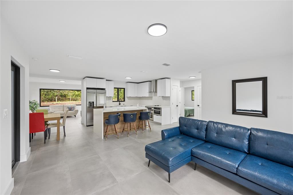 An open-concept living room and kitchen featuring a blue sectional sofa and a kitchen island — 241 SW BUENA VISTA ROAD, DUNNELLON, FL