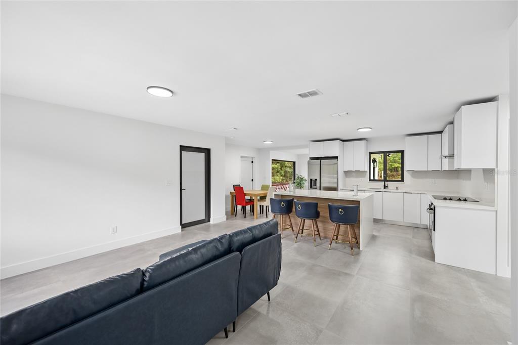 A modern open-concept kitchen and living area features white cabinetry, a central island, and tile flooring — 241 SW BUENA VISTA ROAD, DUNNELLON, FL