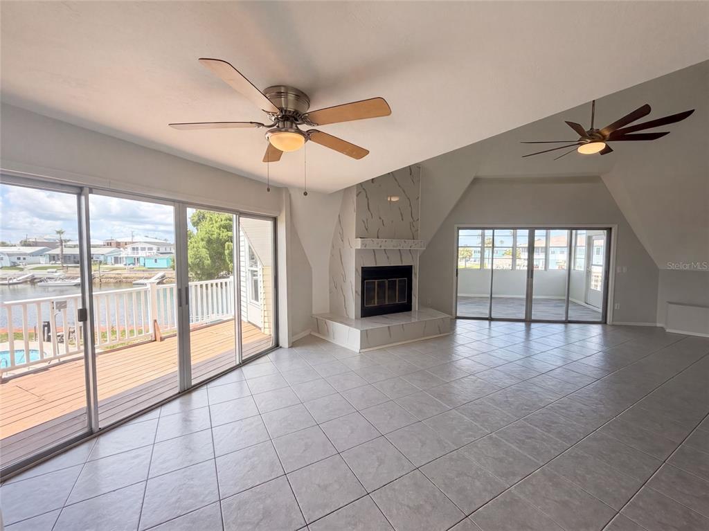 A living room with tile floors, a marble fireplace, and sliding glass doors to a deck — 4100 FLAMINGO BOULEVARD, HERNANDO BEACH, FL