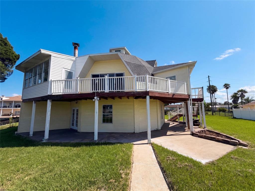 A yellow two-story house features a large elevated deck and a concrete patio area — 4100 FLAMINGO BOULEVARD, HERNANDO BEACH, FL
