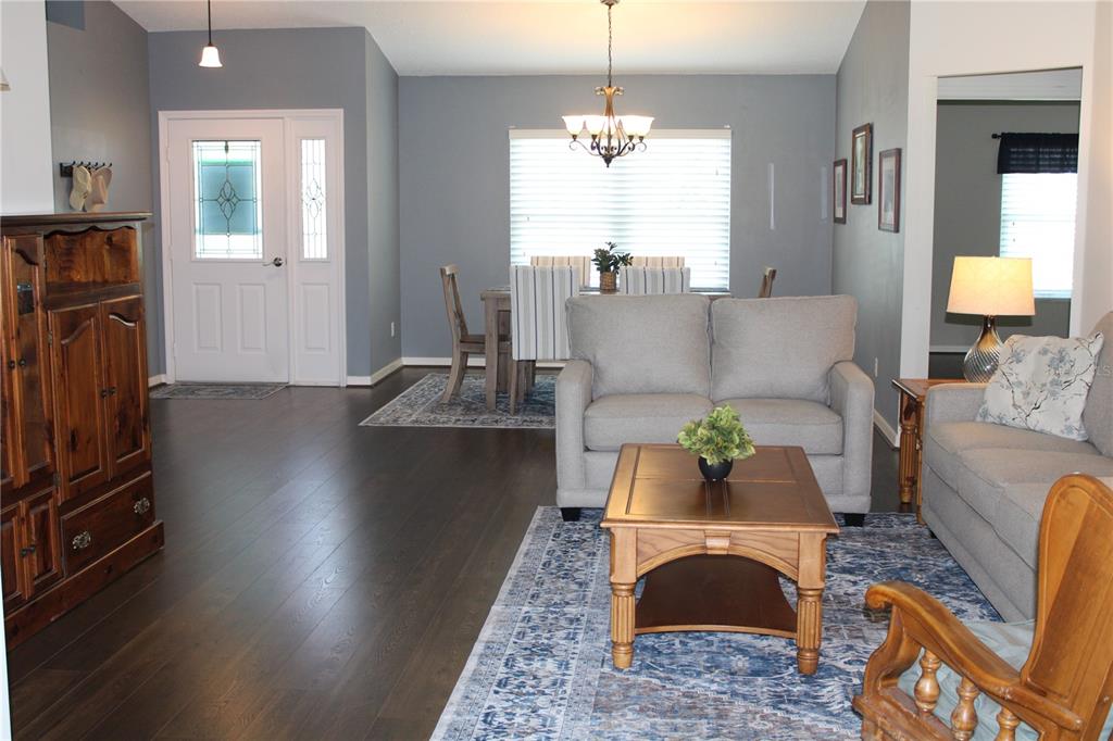 A dining room with a wooden table, six chairs, a chandelier, and a front door — 4704 RIVER RIDGE DRIVE, LEESBURG, FL