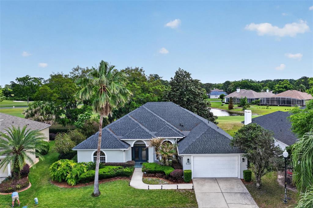 An aerial view shows a single-story house with a gray roof, white garage, and landscaping — 1760 EDGEWATER DRIVE, MOUNT DORA, FL