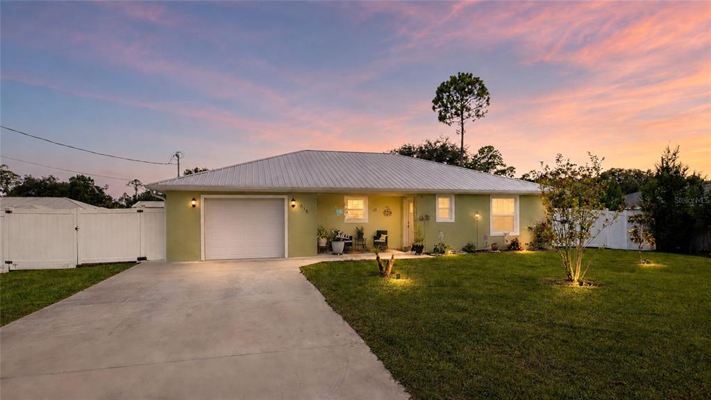 A single-story house with a light green exterior, metal roof, and attached garage at dusk — 615 FOURTH, BUNNELL, FL