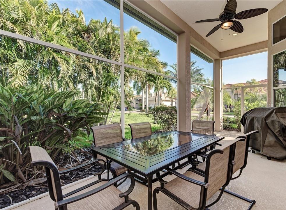 A screened-in patio features a dining set, a ceiling fan, and views of palm trees — 304 8TH AVENUE E, PALMETTO, FL