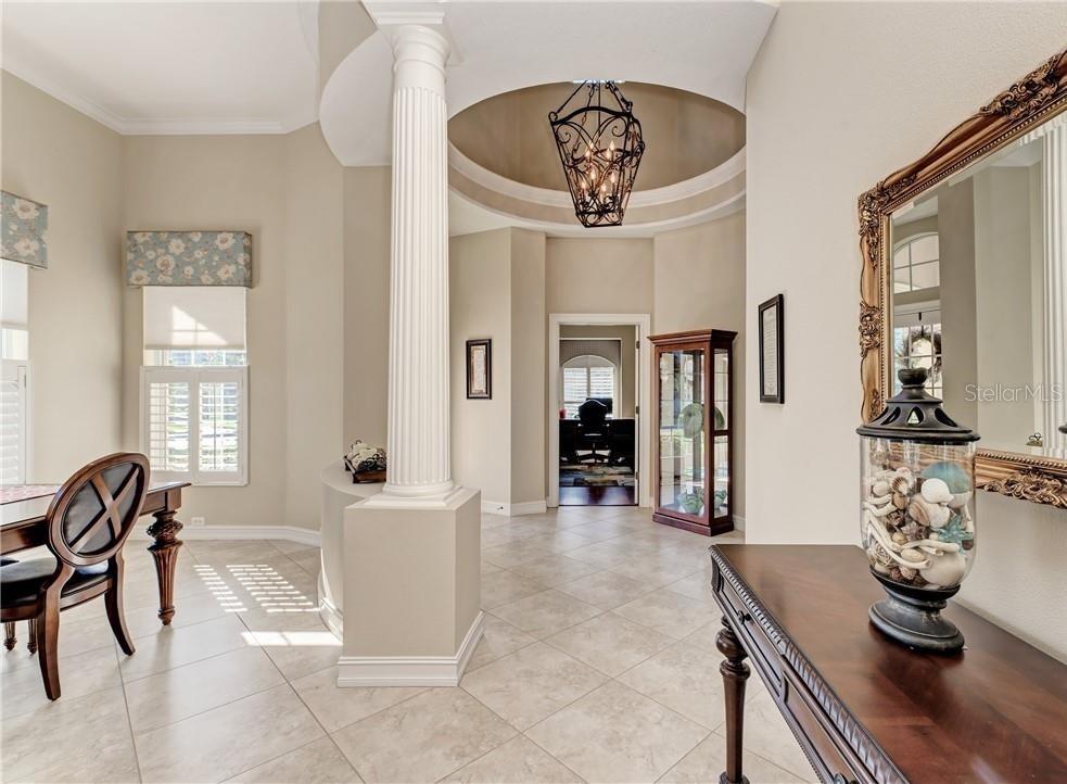 A foyer with tile flooring, a decorative column, a chandelier, and a mirror-topped console table — 304 8TH AVENUE E, PALMETTO, FL