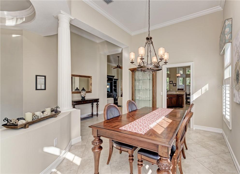 A dining room features a wooden table, a chandelier, a glass display cabinet, and tiled floors — 304 8TH AVENUE E, PALMETTO, FL
