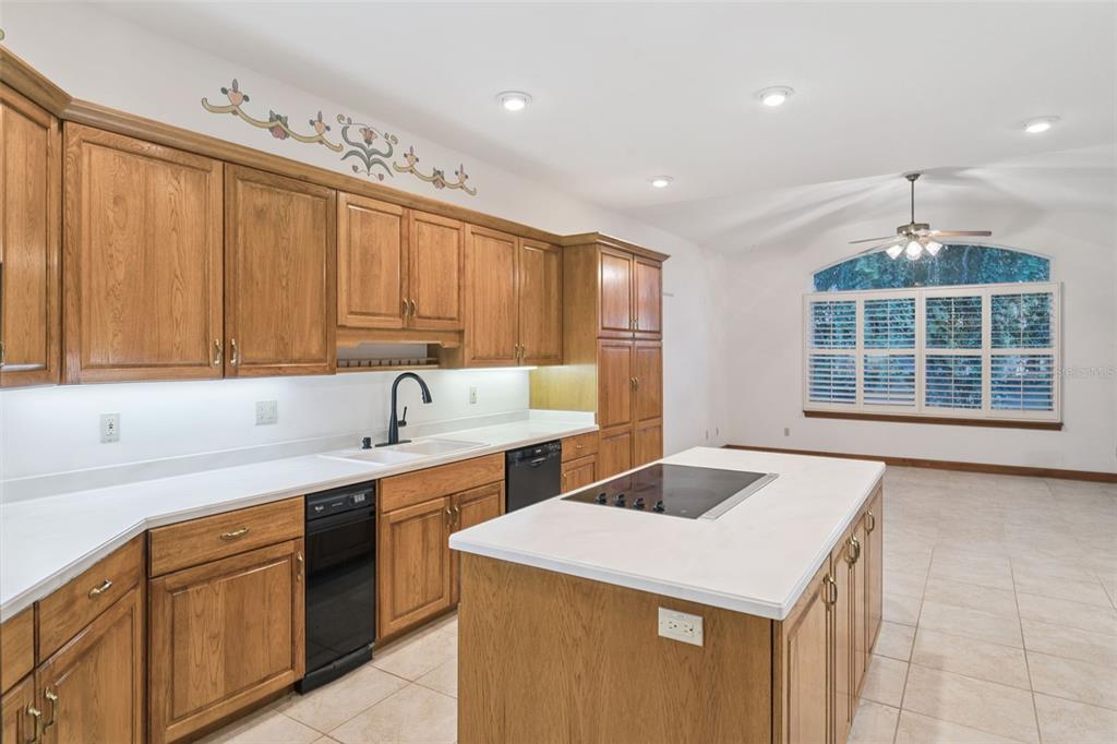 A kitchen with oak cabinets, white countertops, a center island, and a large window — 8516 FIRESTONE CIRCLE, CLERMONT, FL