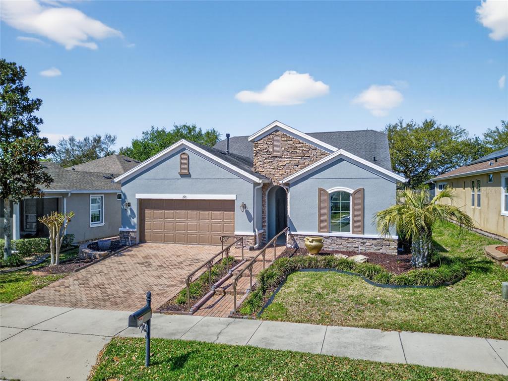 A single-story house with a stone facade, gray stucco, and a brick-paved driveway and ramp — 329 SILVER MAPLE ROAD, GROVELAND, FL