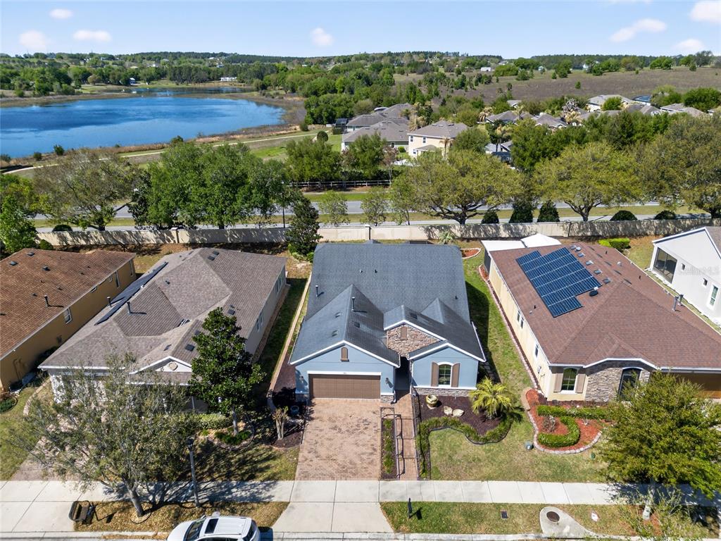 An aerial view shows a blue house with a paved driveway between two neighboring homes — 329 SILVER MAPLE ROAD, GROVELAND, FL