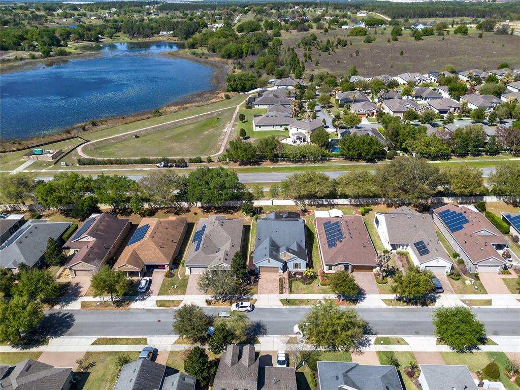 An aerial view shows a suburban neighborhood with houses, a road, and a large lake — 329 SILVER MAPLE ROAD, GROVELAND, FL