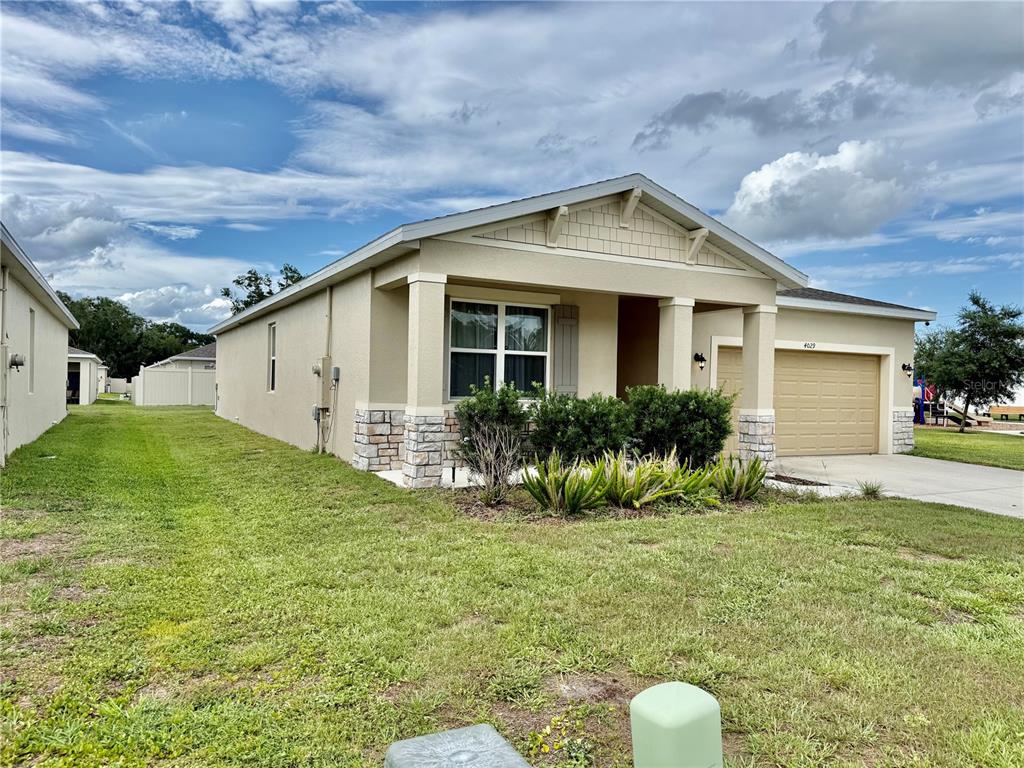 A single-story house with a tan stucco exterior, stone accents, and a two-car garage — 4029 MAYHILL LOOP, EUSTIS, FL