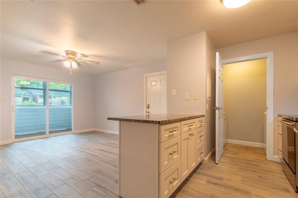 A living room features light wood-look tile flooring, a ceiling fan, and a sliding glass door — 1400 GANDY BOULEVARD N UNIT 1010, ST PETERSBURG, FL