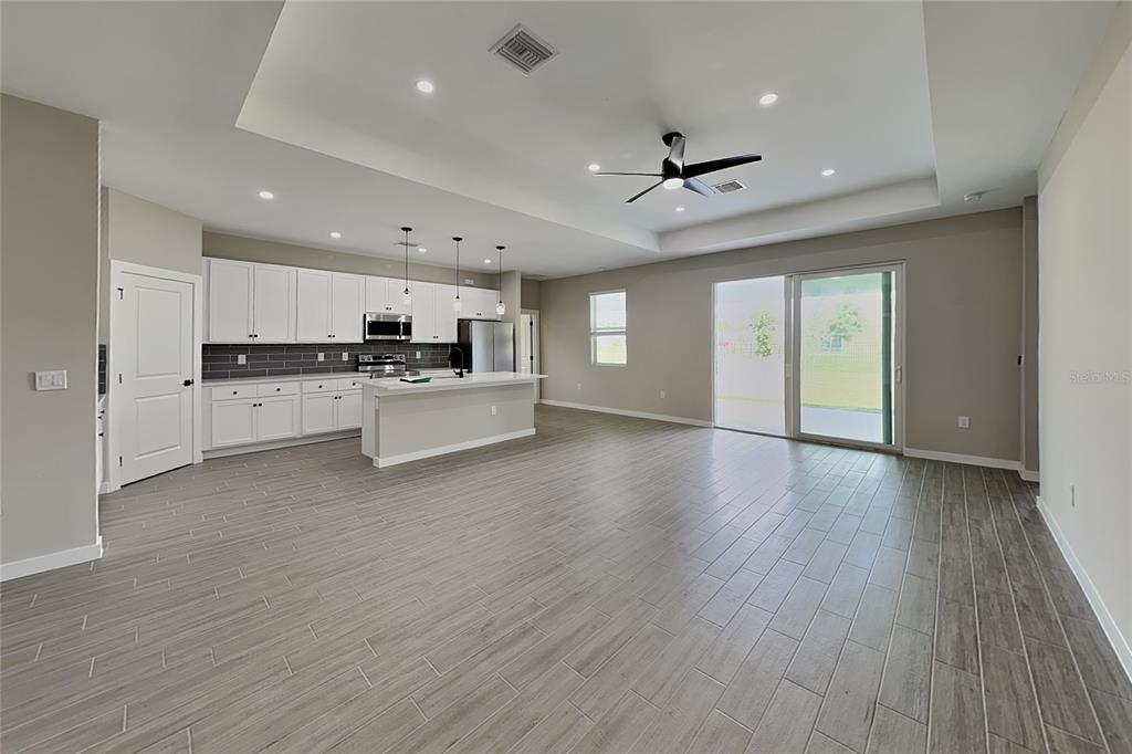 An open-concept kitchen and living area featuring white cabinets, a center island, and tile flooring — 2440 BRONCO LANE, NORTH PORT, FL