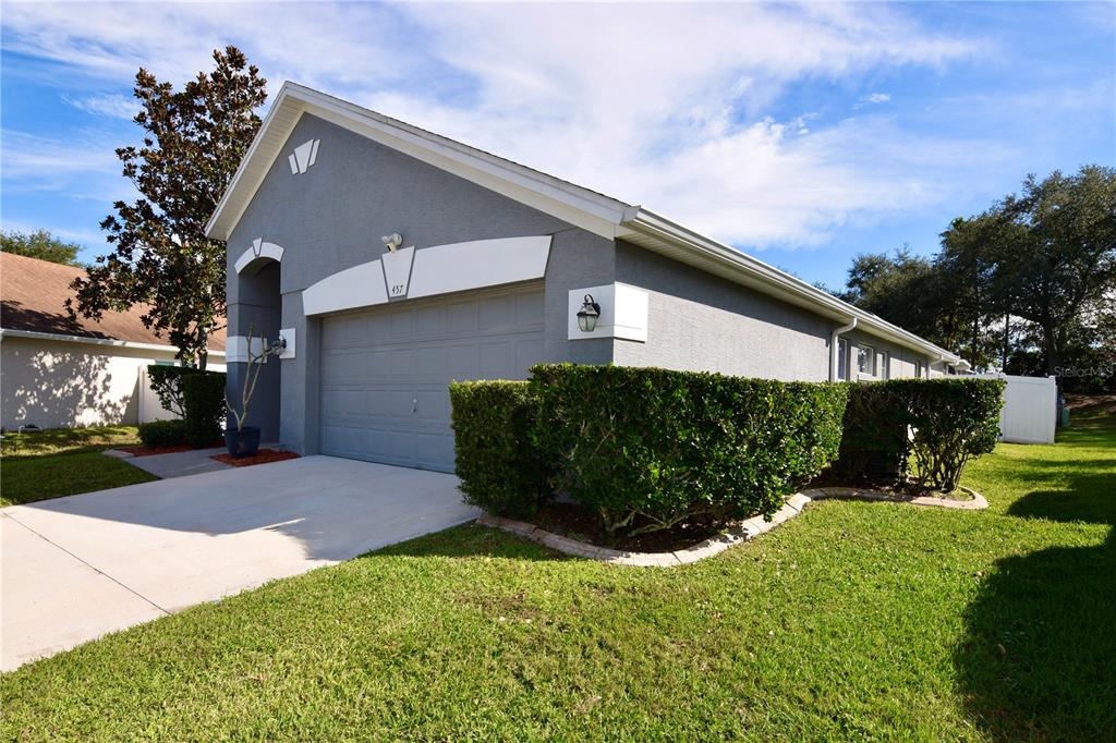 A gray single-story house features a two-car garage, a concrete driveway, and manicured landscaping — 457 MICKLETON LOOP, OCOEE, FL