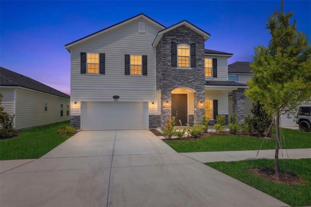 A two-story suburban house features a stone facade, white siding, and a two-car garage — 3880 HOLSTEIN WAY, GREEN COVE SPRINGS, FL