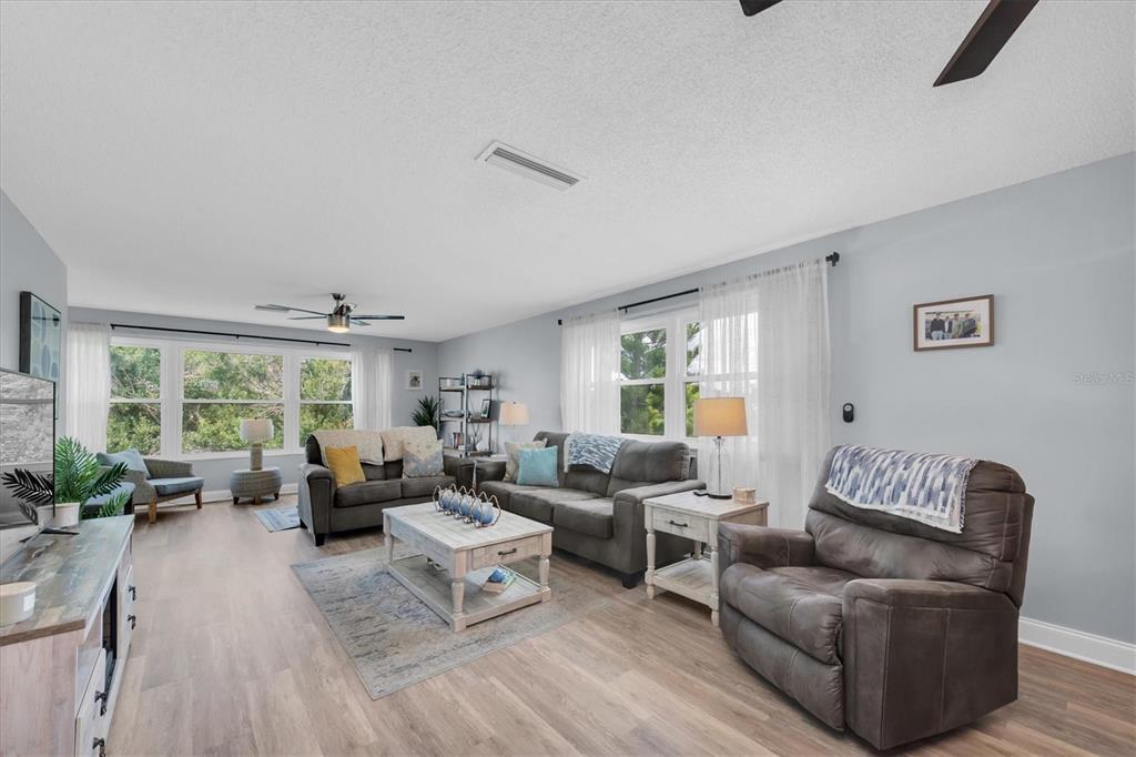 A living room features gray walls, wood-look flooring, two sofas, and a recliner — 5603 80TH STREET N UNIT 415, ST PETERSBURG, FL
