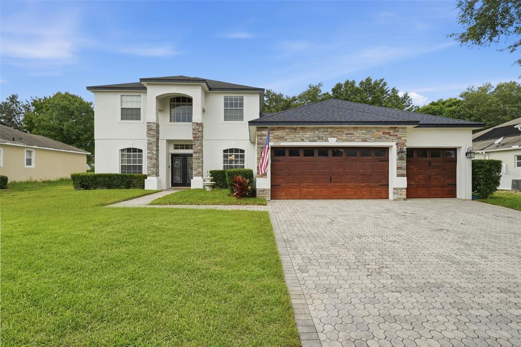 A two-story house with a stone-accented facade, a three-car garage, and a paved driveway — 3930 OLD DUNN RD, APOPKA, FL