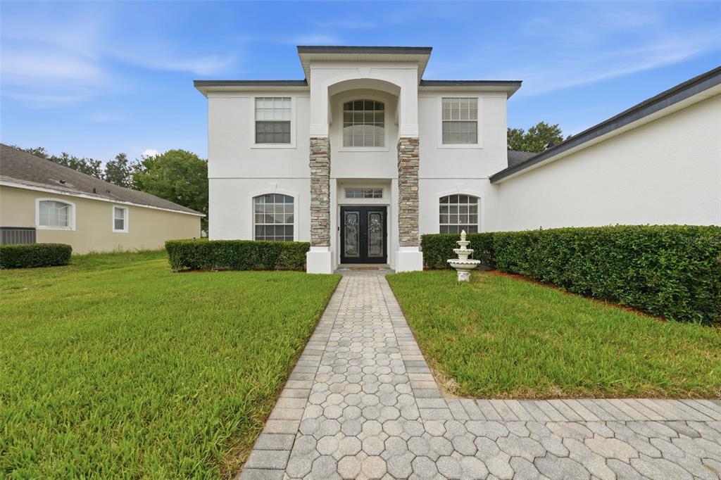 A two-story white house with stone accents features a paved walkway leading to the entrance — 3930 OLD DUNN RD, APOPKA, FL