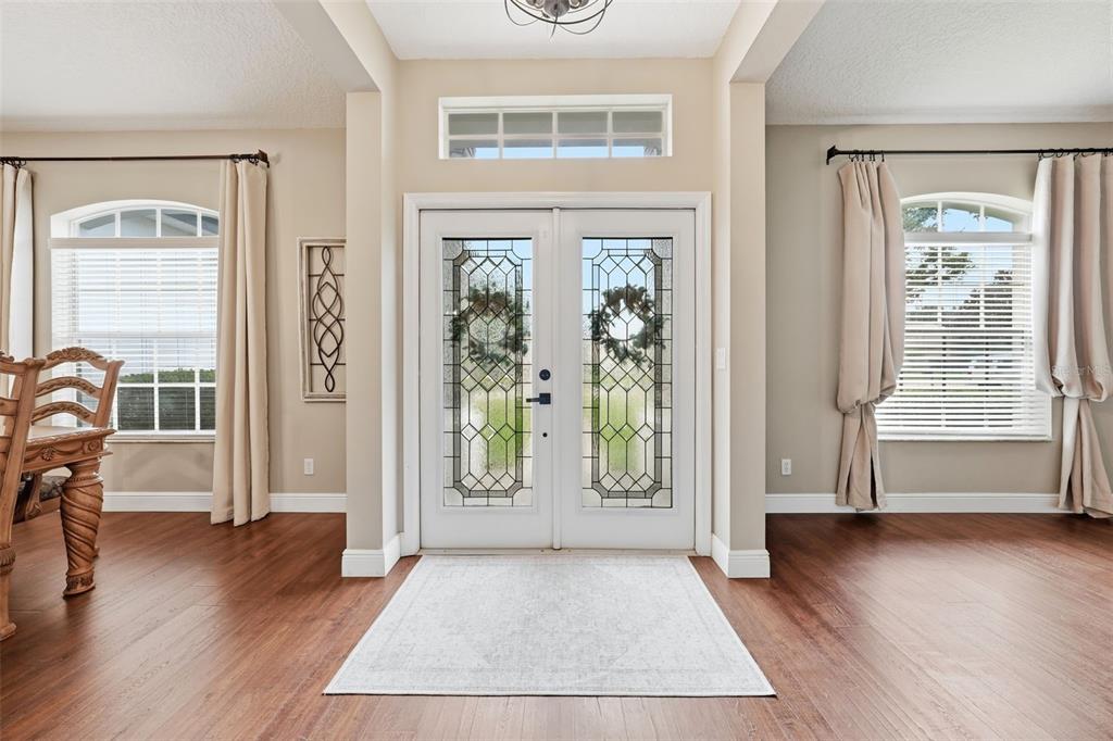 An entryway features double glass-paneled doors, wood flooring, and windows with beige curtains — 3930 OLD DUNN RD, APOPKA, FL