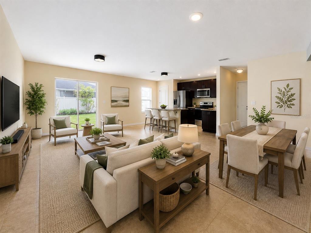 An open-concept living and dining area features a white sofa, wooden dining table, and kitchen — 10624 MASSIMO DRIVE, WIMAUMA, FL