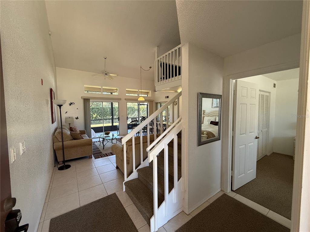 An interior view of a living room with a staircase, tile flooring, and sliding glass doors — 3164 TAMARIND CIRCLE, KISSIMMEE, FL