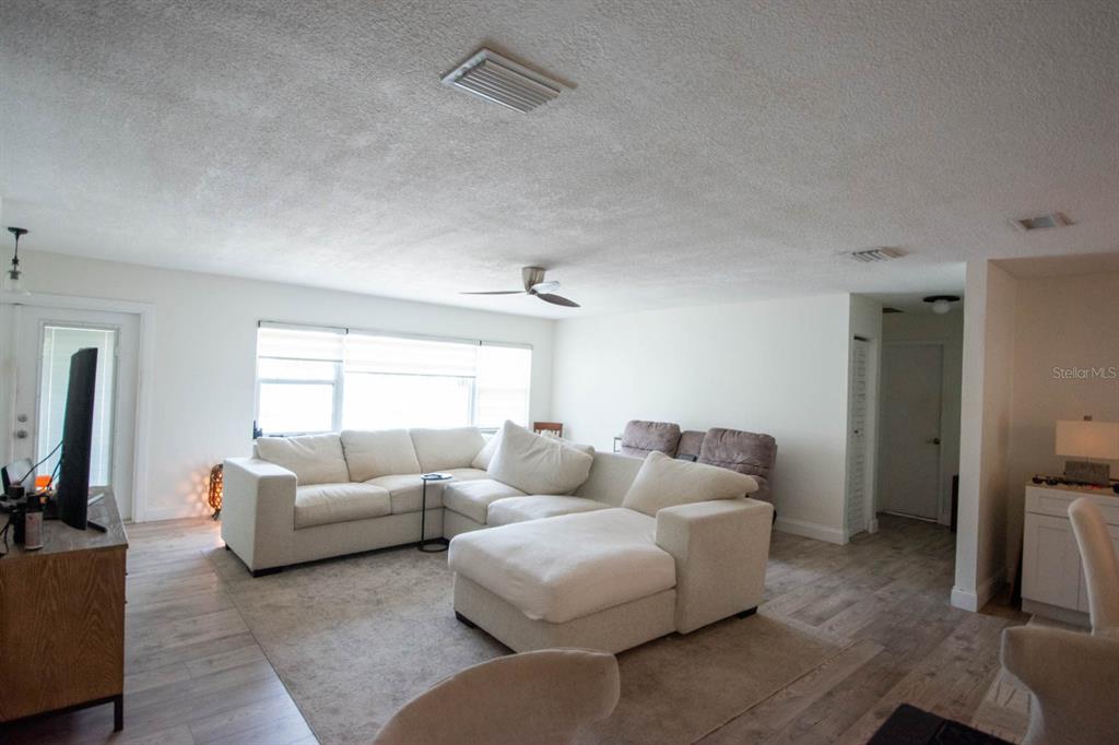 A living room features a white sectional sofa, light wood-look flooring, and a ceiling fan — 308 WENDI LANE, RUSKIN, FL