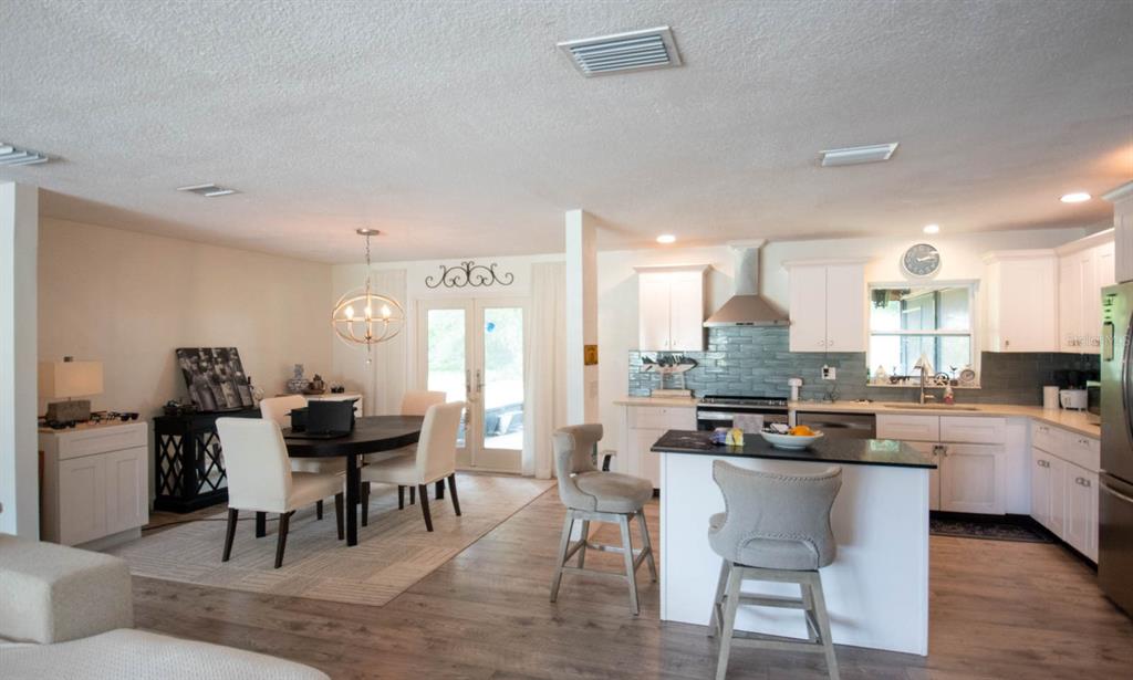 An open-concept kitchen and dining area features white cabinets, a kitchen island, and wood flooring — 308 WENDI LANE, RUSKIN, FL