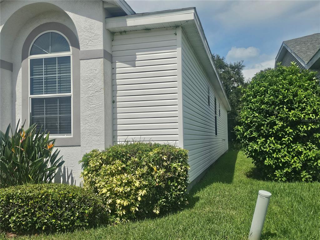 A side view of a house exterior featuring white horizontal siding and a large window — 603 CANAL WAY, OLDSMAR, FL
