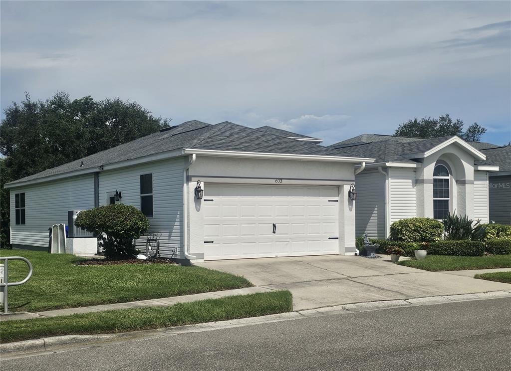 A single-story house with white siding, a two-car garage, and a gray shingled roof — 603 CANAL WAY, OLDSMAR, FL