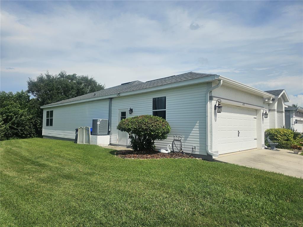 A side view of a white vinyl-sided house with a garage and a grassy lawn — 603 CANAL WAY, OLDSMAR, FL