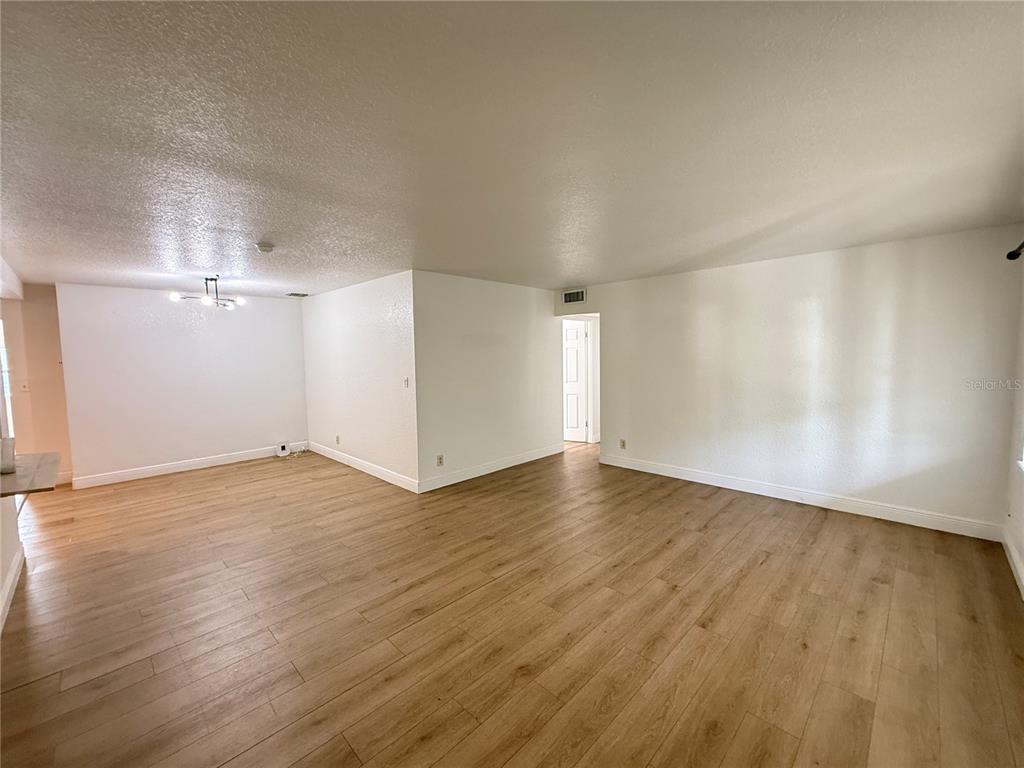 An empty room features light wood-look flooring, white walls, and a ceiling light fixture — 524 N LAKEMONT AVENUE, WINTER PARK, FL