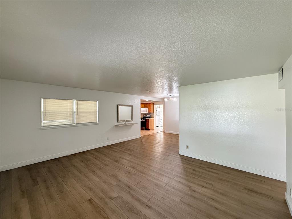 An open-concept living area with wood-look flooring, white walls, and a view into the kitchen — 524 N LAKEMONT AVENUE, WINTER PARK, FL