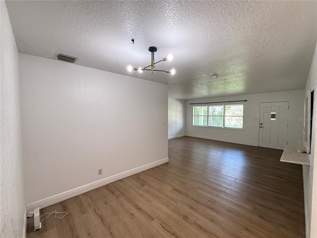 An open-concept living and dining area features light wood-look flooring, white walls, and a chandelier — 524 N LAKEMONT AVENUE, WINTER PARK, FL