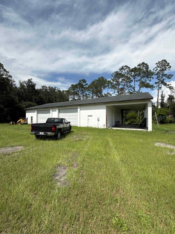 A white metal building with two garage doors and an open bay sits on grass — 1116 N HIGHWAY 17 UNIT 1, PALATKA, FL